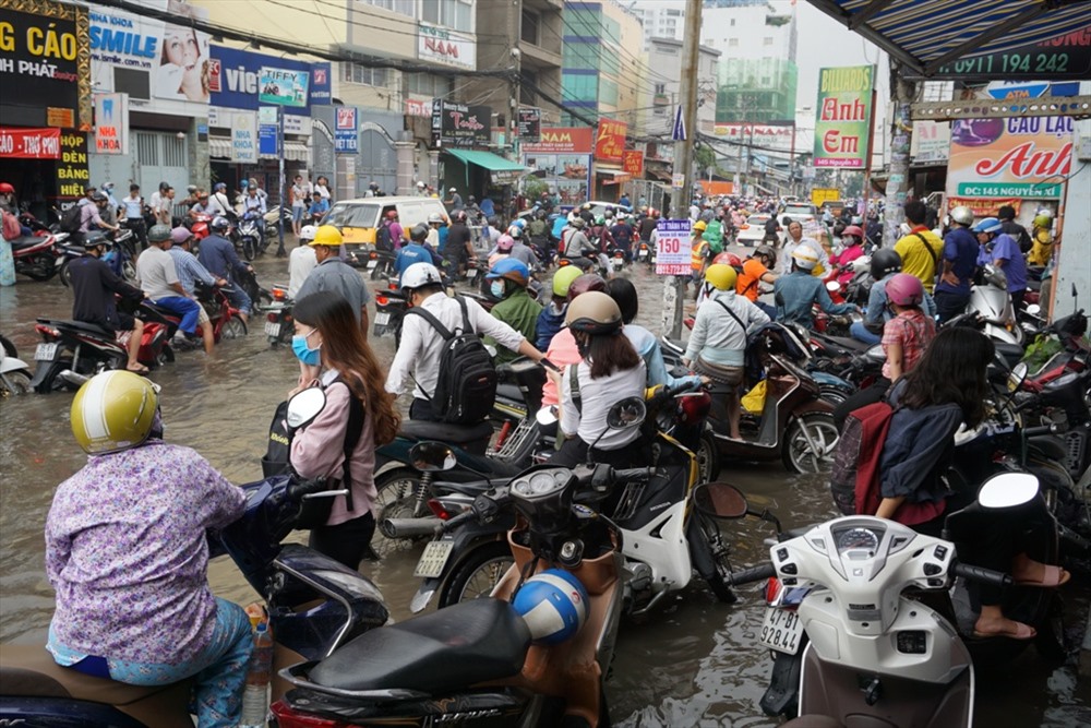 Đến 9h30 cùng ngày, đường Nguyễn Xí còn ngập sâu, nhiều người đứng chờ trên vỉa hè chờ nước rút rồi mới đi tiếp.