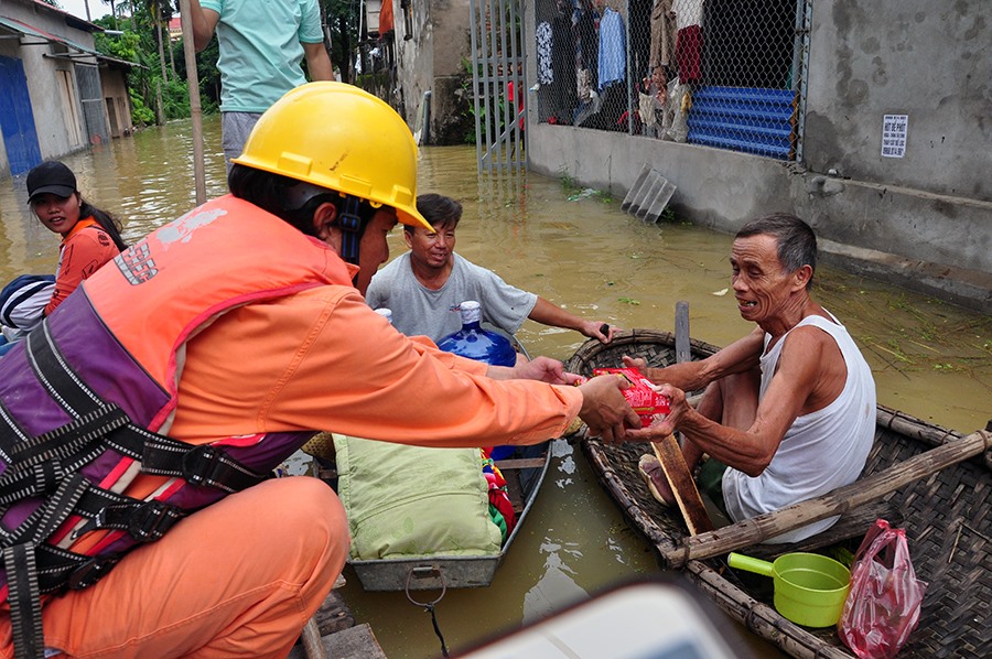 Thợ điện Chương Mỹ vừa thực hiện nhiệm vụ, vừa tổ chức cứu trợ cho những người dân trong vùng ngập nặng. Ảnh: Hoa Việt Cường