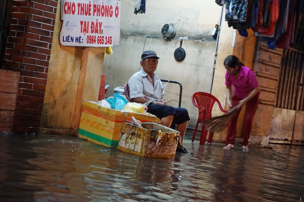 Nước ngập ảnh hưởng đến sinh hoạt và buôn bán của người dân trên đường Nguyễn Tất Thành (Q.4).  Ảnh: M.Q