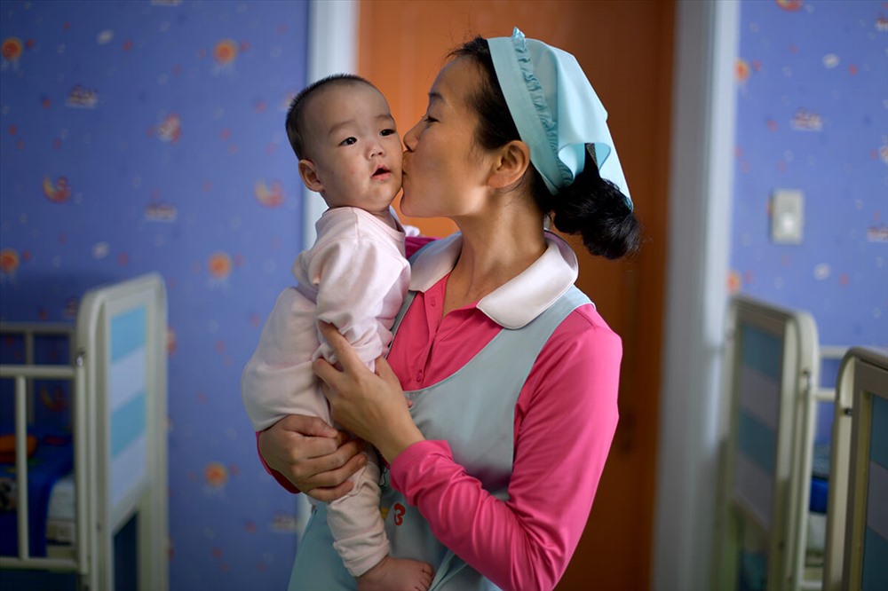Nữ y tá đang nựng một em bé tại trại trẻ mồ côi ở Bình Nhưỡng. Một số em ở đây bị suy dinh dưỡng.