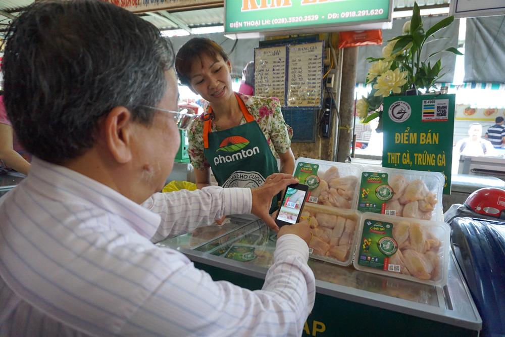 Để truy xuất nguồn gốc, người tiêu dùng sử dụng điện thoại thông minh có cài phần mềm Te-food để soi vào con tem được dán trên vỉ trứng và thịt gà.  Ảnh: M.Q