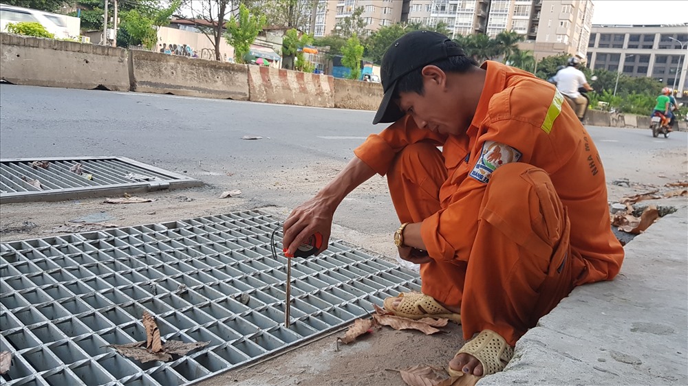 Công nhân đo nước trong cống trước khi tiến hành nổ máy bơm nước ra lại sông Sài Gòn, cứu đường Nguyễn Hữu Cảnh khỏi ngập. Ảnh: Trường Sơn