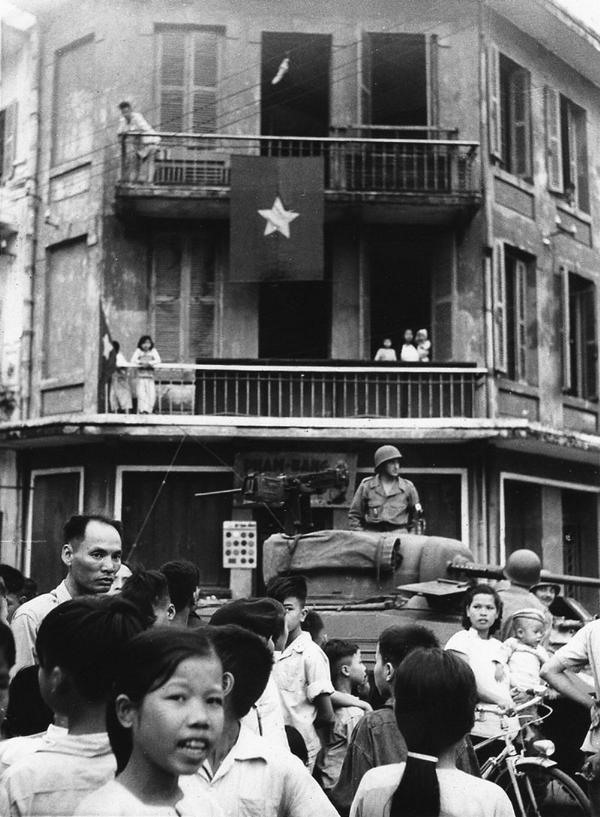 Lá cờ đỏ sao vàng bay phấp phới trên một nhà dân Thủ đô, ngay dưới đó là một xe lính Pháp chuẩn bị rút khỏi Hà Nội.