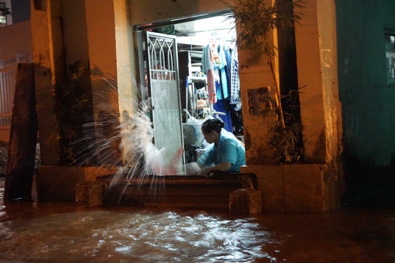 Người dân trên đường Nguyễn Văn Hưởng hì hục tát nước ngập trong nhà ra đường.