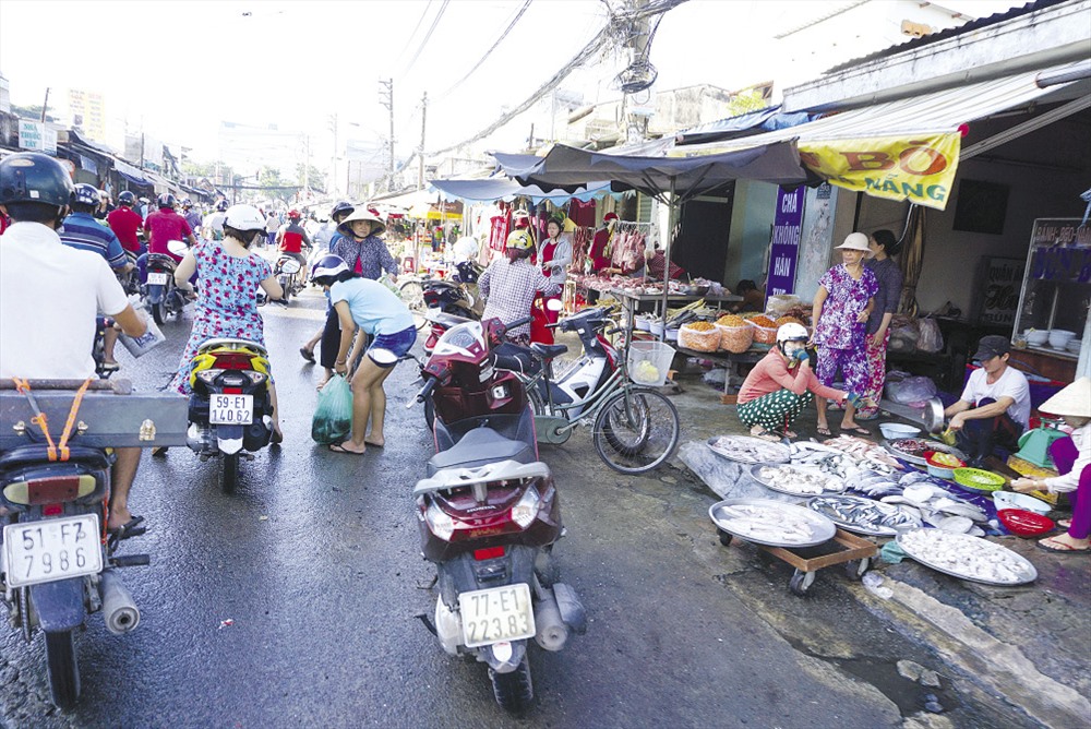 Chợ tự phát lấn chiếm lòng đường, vỉa hè tại đường Nguyễn Xí (Q.Bình Thạnh), người mua dừng xe hai bên đường, khiến giao thông lộn xộn.