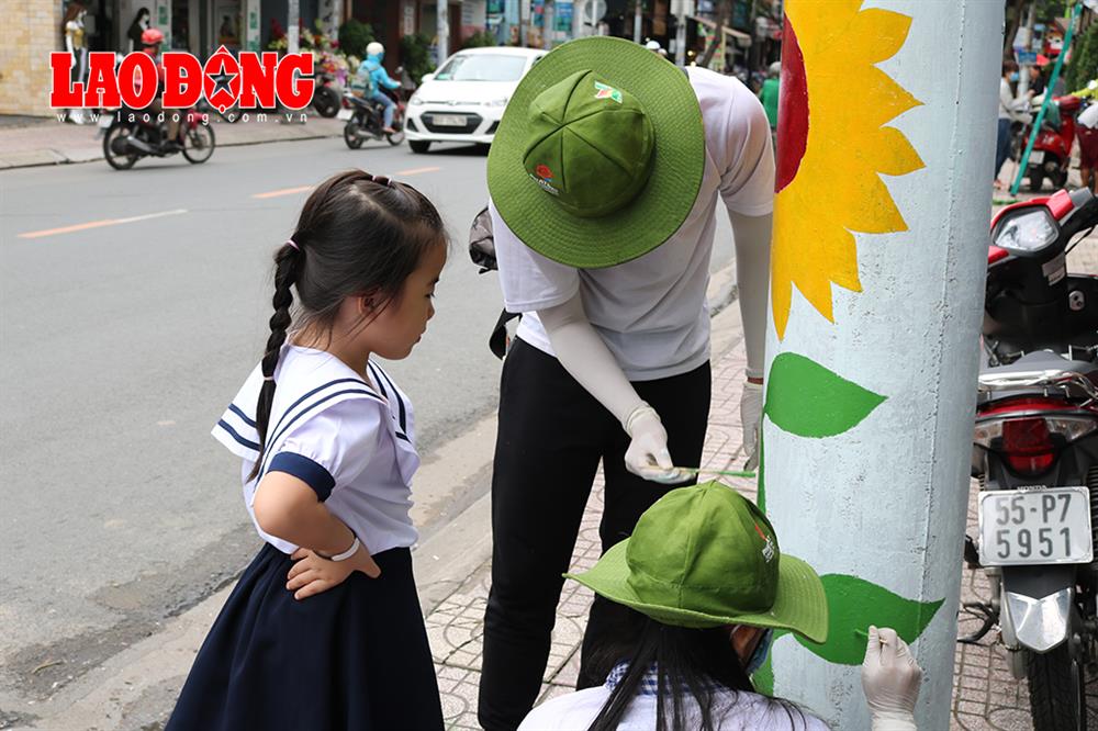 Thấy các anh chị đang vẽ hoa, một em học sinh tiến đến xem với ánh mắt ngạc nhiên. Ảnh: Đoàn phường 1 Tân Bình