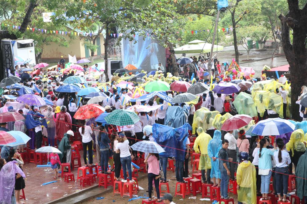 Người dân, học sinh đứng dưới cơn mưa nặng hạt, hướng lên màn hình trực tiếp ở đầu cầu truyền hình Quảng Trị cổ vũ cho Nhật Minh. Ảnh: Hưng Thơ.