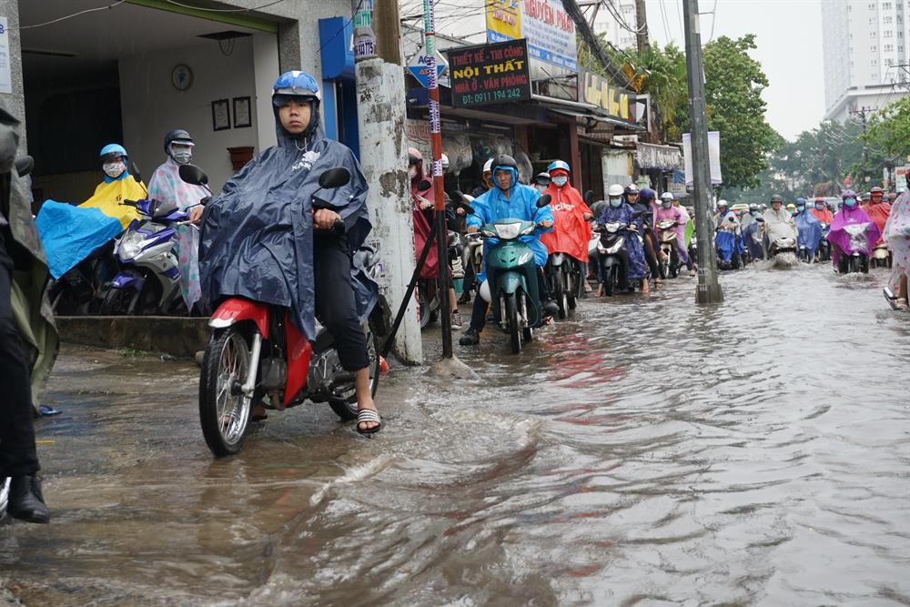 Nhiều người điều khiển chạy xe máy lên vỉa hè để tránh đoạn nước ngập sâu.