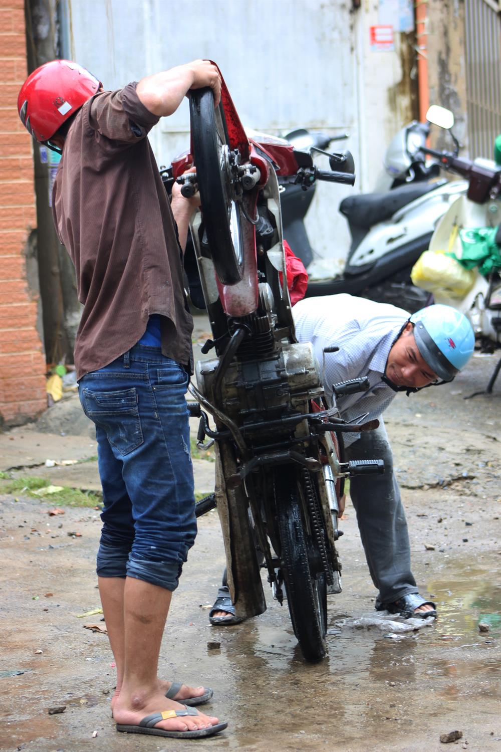 Hai anh em hỗ trợ nhau khắc phục cheiecs xe bị chết máy trên đường Nguyễn Hữu Cảnh. Ảnh: Trường Sơn