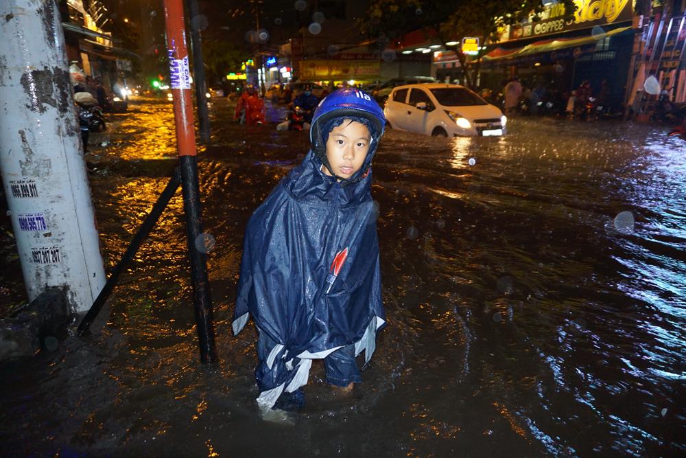 Chỉ hơn nửa giờ sau mưa, đường Nguyễn Xí (Q.Bình Thạnh) hiện giống như sông. Trong ảnh, một cậu bé mò mẫm tìm tìm đường đi trên đường Nguyễn Xí.