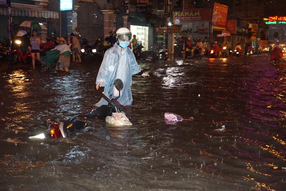 Một người phụ nữ bị sóng đánh ngã xe xuống đường Nguyễn Xí. Chiếc xe chìm nghỉm trong nước, đồ đạc bị ướt sũng.