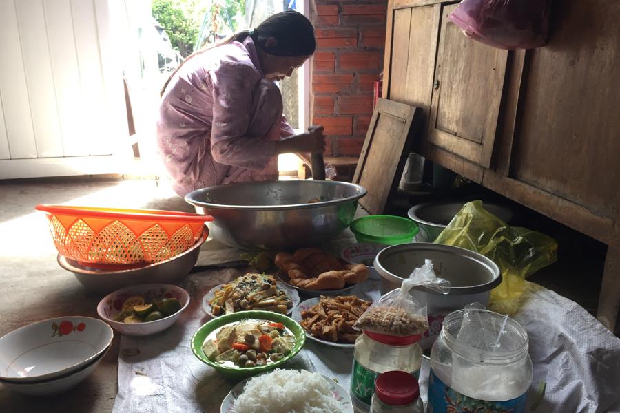 Cô Nguyễn Ngọc Bỉ ngồi giã mắm gừng cho bữa cơm tân gia. Ảnh: L.T