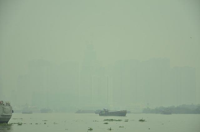 Các phương tiện di chuyển trên sông Sài Gòn, phía sau là dãy nhà cao tầng gần như “biến mất” trong màn sương trắng đục.