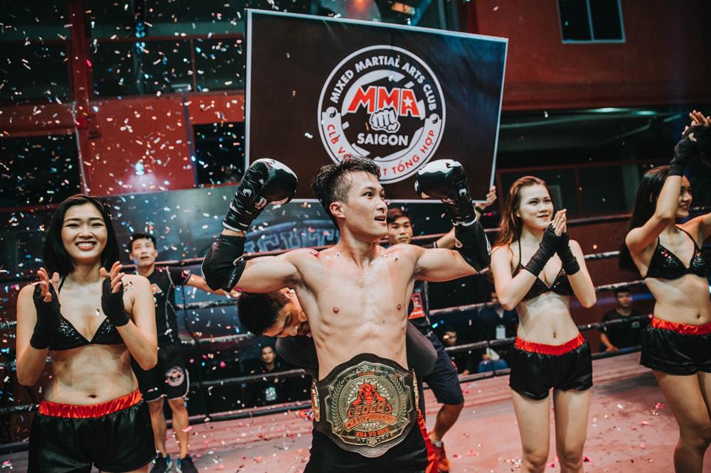 Tổng đạo diễn chương trình - Johnny Trí Nguyễn tận tình đeo đai cho nhà vô địch đầu tiên của hạng MIDDLEWEIGHT 62kg là Vũ Lê Văn.