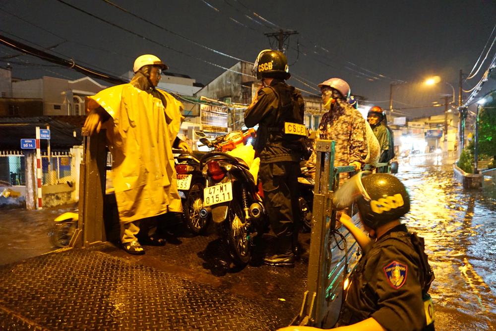Cảnh sát giao thông cùng cảnh sát cơ động dùng xe tải chở xe máy cho người dân qua đường ngập Tô Ngọc Vân.  Ảnh: M.Q
