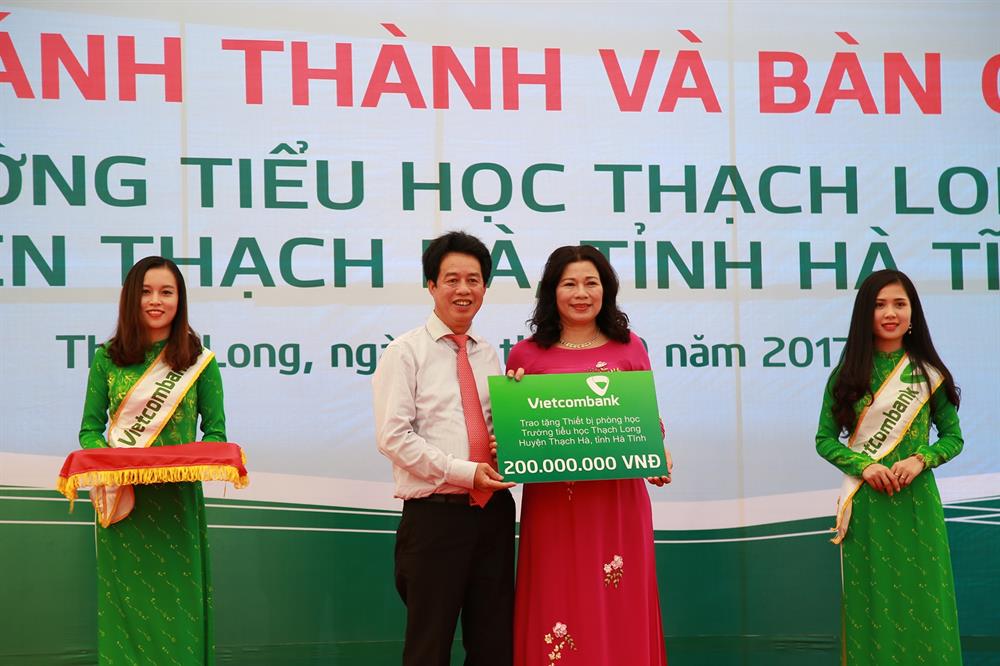 Ông Nguyễn Mỹ Hào – Ủy viên HĐQT Vietcombank (thứ 2 từ trái sang) trao tượng trưng số tiền 200 triệu đồng tài trợ trang thiết bị phòng học cho Trường Tiểu học Thạch Long (Hà Tĩnh)
