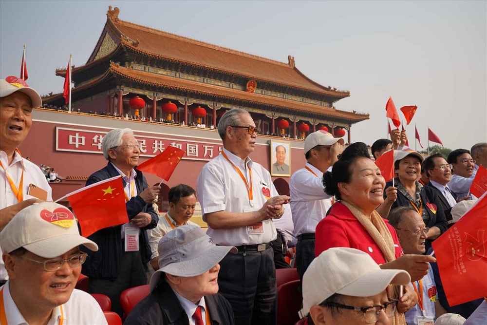 Những người theo dõi vẫy cờ và hát trước khi lễ diễu binh bắt đầu ở Quảng trường Thiên An Môn. Ảnh: Getty.