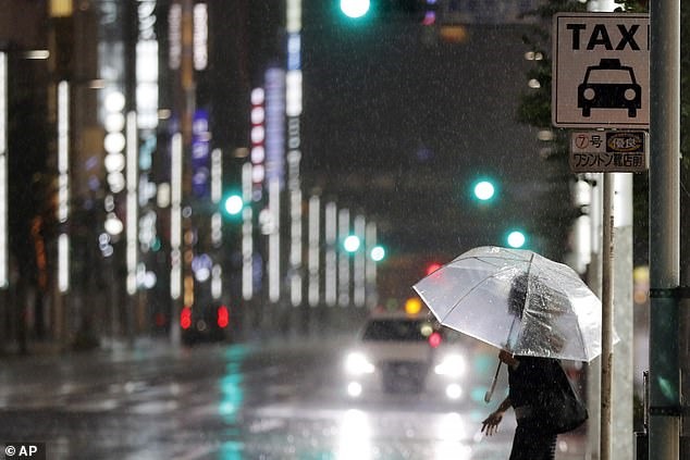 Một phụ nữ đang tìm cách vẫy taxi ở Tokyo trong mưa khi bão Hagibis đổ bộ. Ảnh: AP.