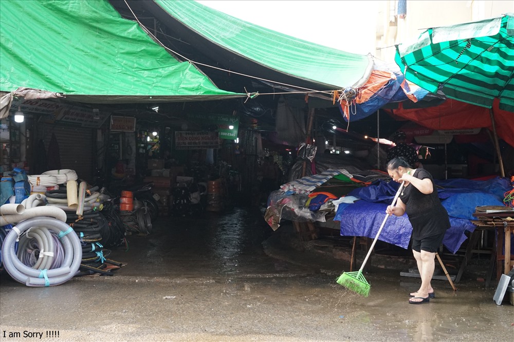 Tiểu thương chợ Vinh quét dọn gian hàng sau trận nước ngập. Ảnh: QĐ