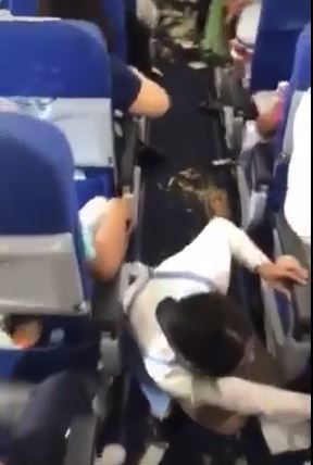 Một tiếp viên trên chuyến bay QH212 của Bamboo Airways chiều 2.10 đang hỗ trợ hành khách dọn dẹp sau sự cố. Ảnh: Cắt từ clip.
