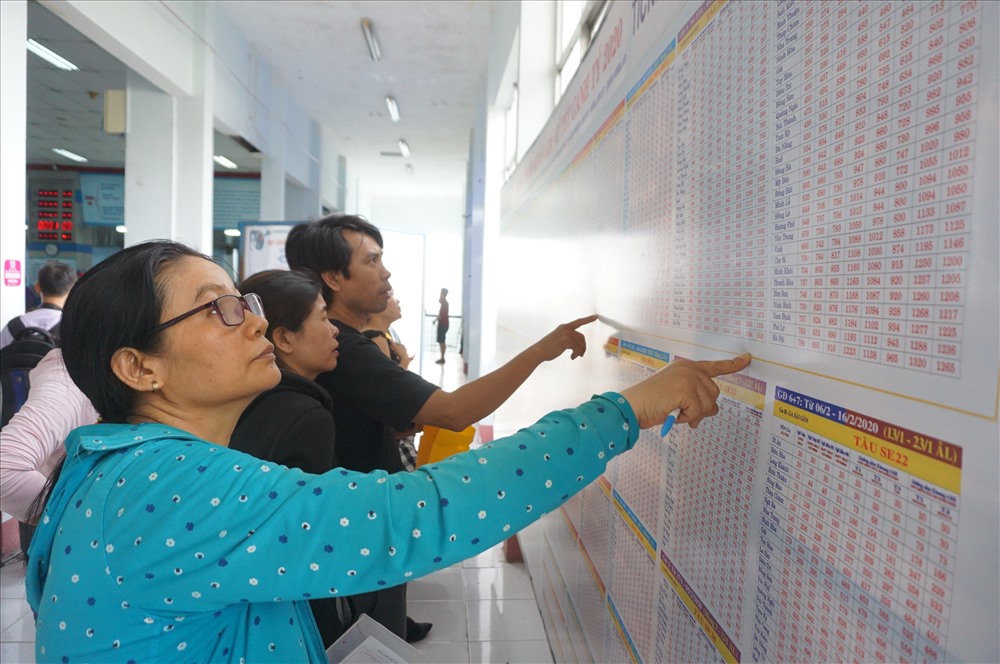 Hành khách xem bảng giá vé tàu vè lịch chạy tàu Tết ở ga Sài Gòn.  Ảnh: M.Q