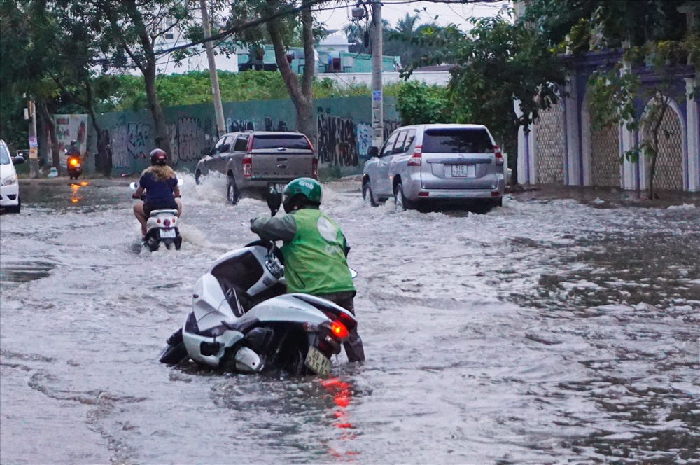Nước ngập lút vỉa hè khiến người dân chạy xe máy bị mất phương hướng, ngã xe.