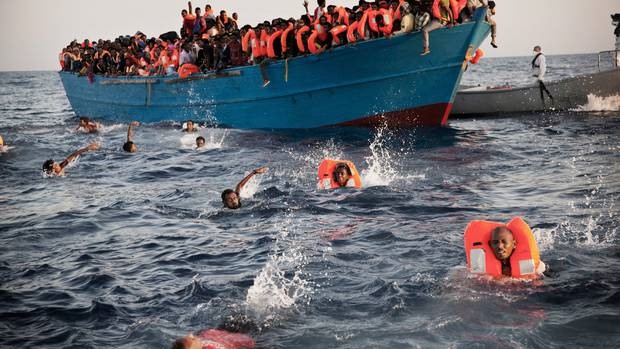 Những người di cư, hầu hết đến từ Eritrea (một nước thuộc đông bắc Châu Phi) nhảy vội xuống nước từ chiếc thuyền gỗ chật cứng người khi họ được các thành viên của một tổ chức phi chính phủ giải cứu. Ảnh: AP