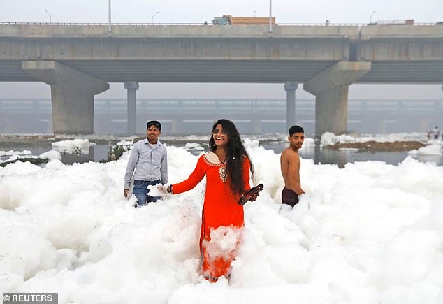 Người dân Ấn Độ ngâm mình giữa đống bọt độc hại. Ảnh: Reuters