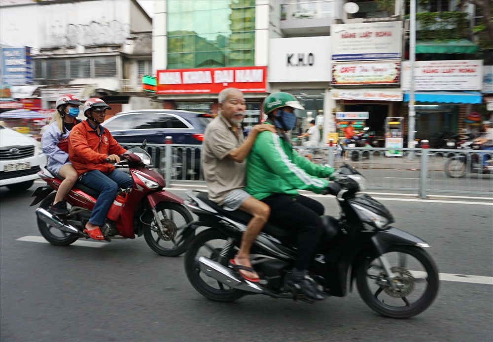 Một tài xế xe ôm công nghệ chở người ngồi trên xe không đội mũ bảo hiểm.  Ảnh: M.Q