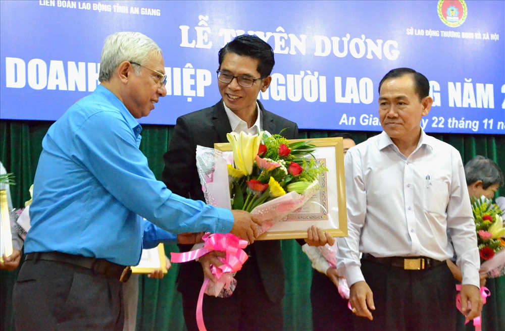 Chủ tịch LĐLĐ An Giang Nguyễn Thiện Phú tặng hoa và trao Bằng Khen UBND tỉnh cho doanh nghiệp vì người lao động. Ảnh: LT