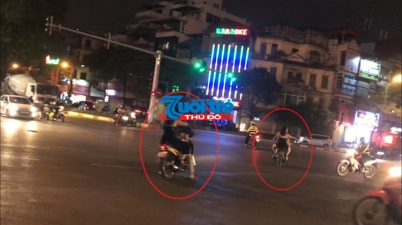 Các thanh niên đầu trần lái xe máy chở theo các cô gái “tay vịn'' chạy ngược chiều, vượt đèn đỏi, vi phạm Luật Giao thông đường bộ.