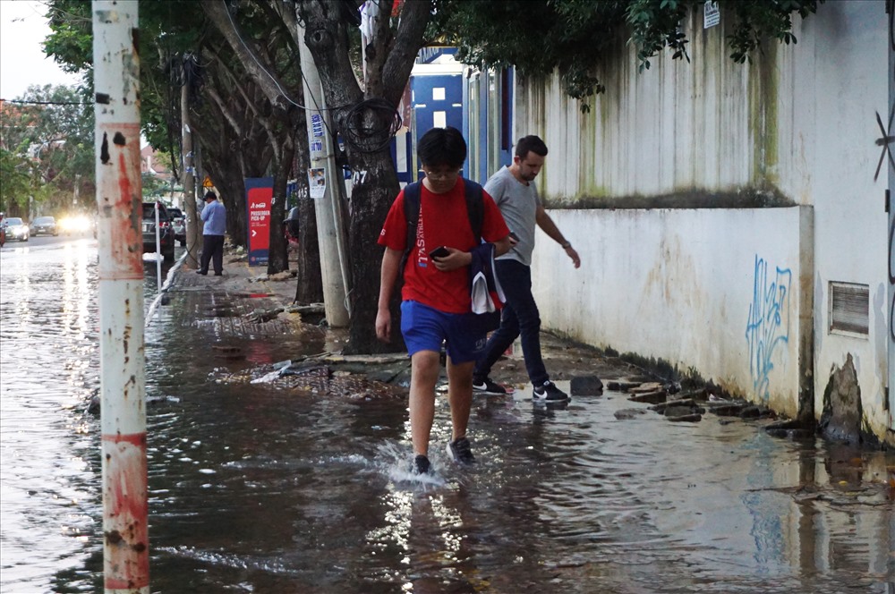 Một số em học sinh trường quốc tế bì bõm lội nước ngập về nhà sau giờ tan trường.