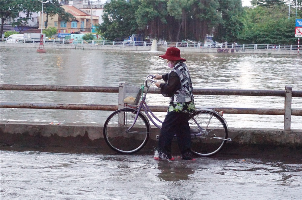 Người dân dắt xe đạp lên vỉa hè qua đoạn đường ngập.  Ảnh: Minh Quân