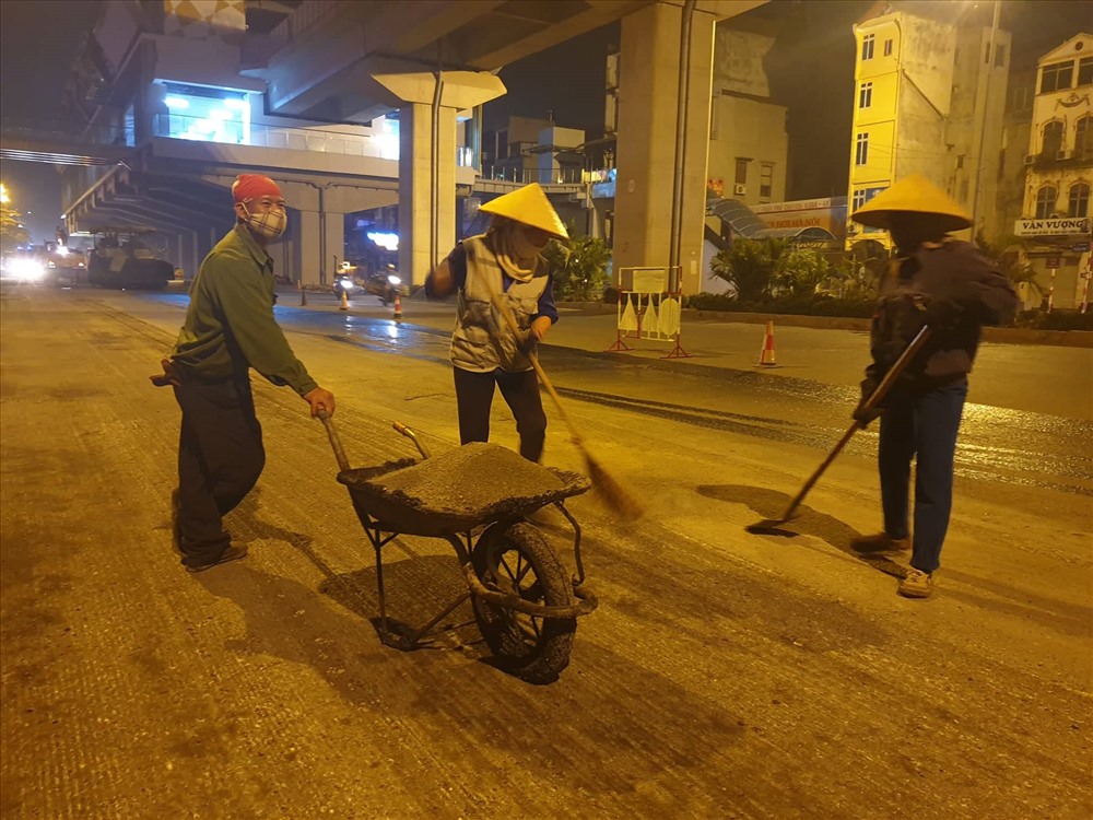 Hàng chục công nhân làm sạch lại mặt đường trước khi thảm lại mặt đường.