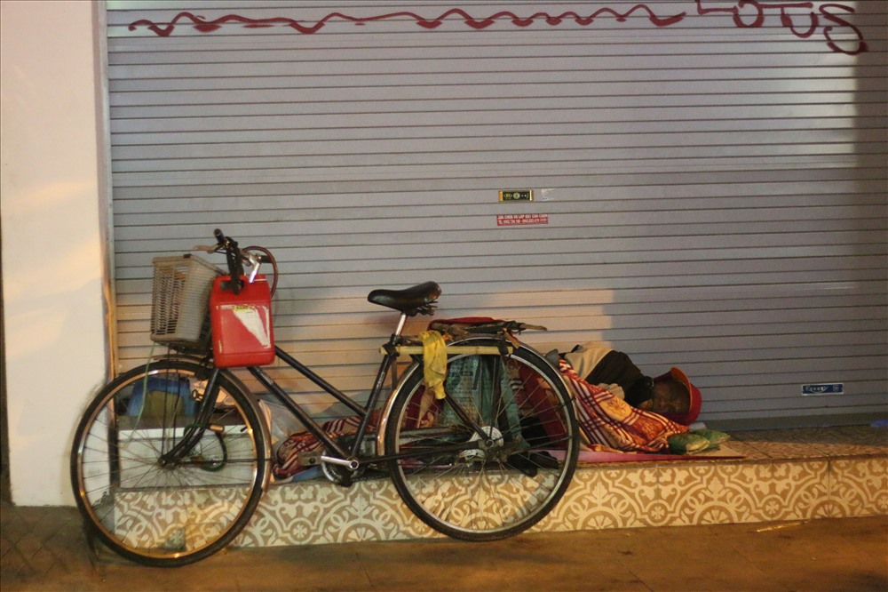 Họ sử dụng ngay chiếc xe đạp cũ kỹ của mình để che gió, che mưa (Ảnh chụp tại đường Nguyễn Hữu Huân).