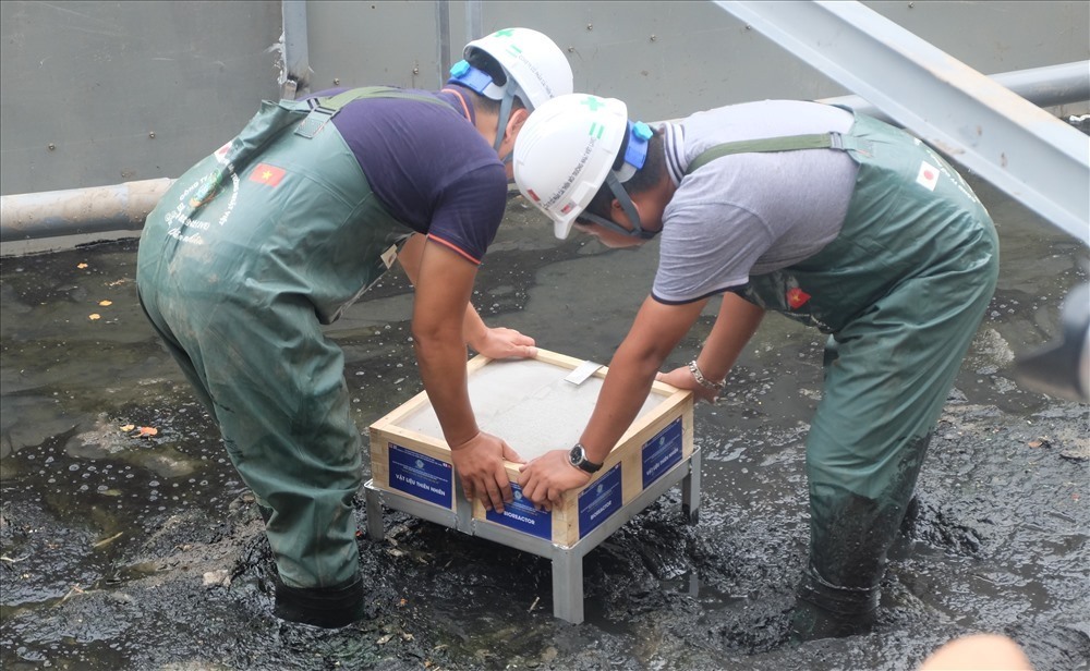 Công nhân môi trường đặt tấm vật liệu Bioreactor xuống khu vực bùn được quây lại.