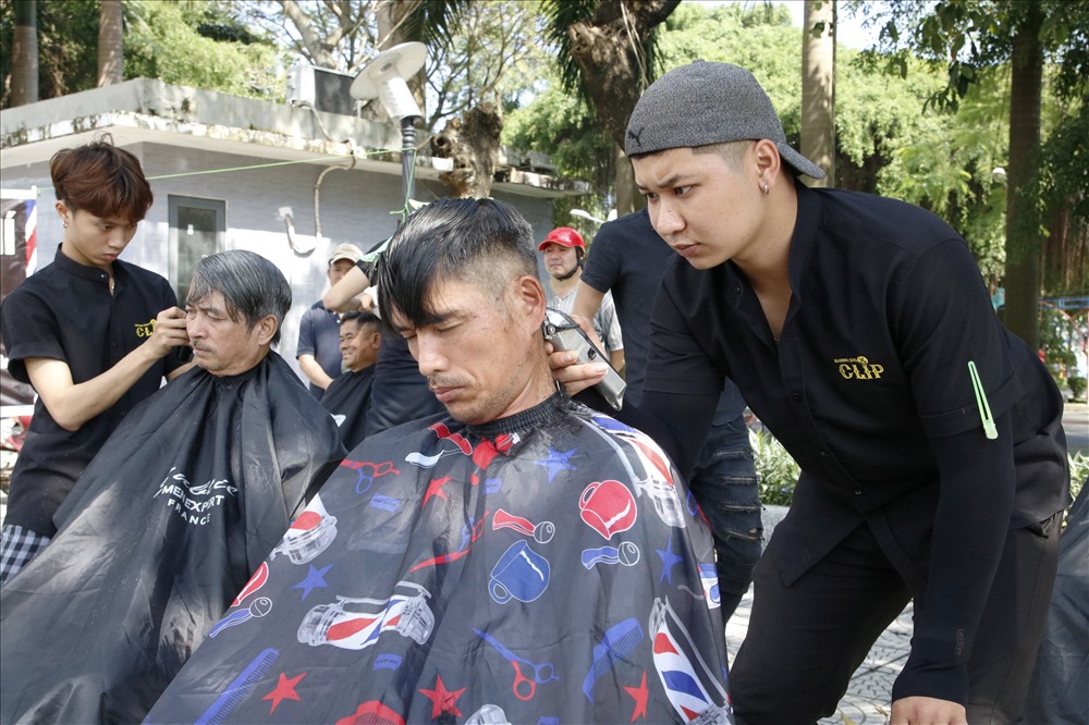 Anh Nguyễn Văn Hiếu (bên phải) dành hơn nửa giờ cho mái tóc của vị khách này. Ảnh: TA