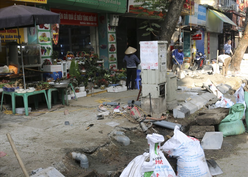 Công nhân đang xử lý rác, vật liệu xây dựng để thực hiện việc lát vỉa hè trên phố Trần Xuân Soạn.