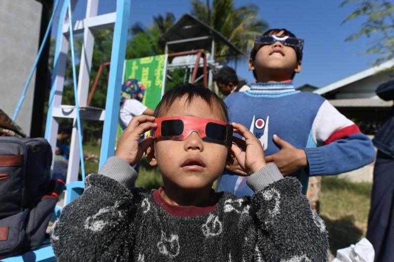 Trẻ em sử dụng kính nhật thực để quan sát hiện tượng thiên văn kỳ thú diễn ra ngày 26.12 ở Wan Twin, miền trung Myanmar. Ảnh: AFP.