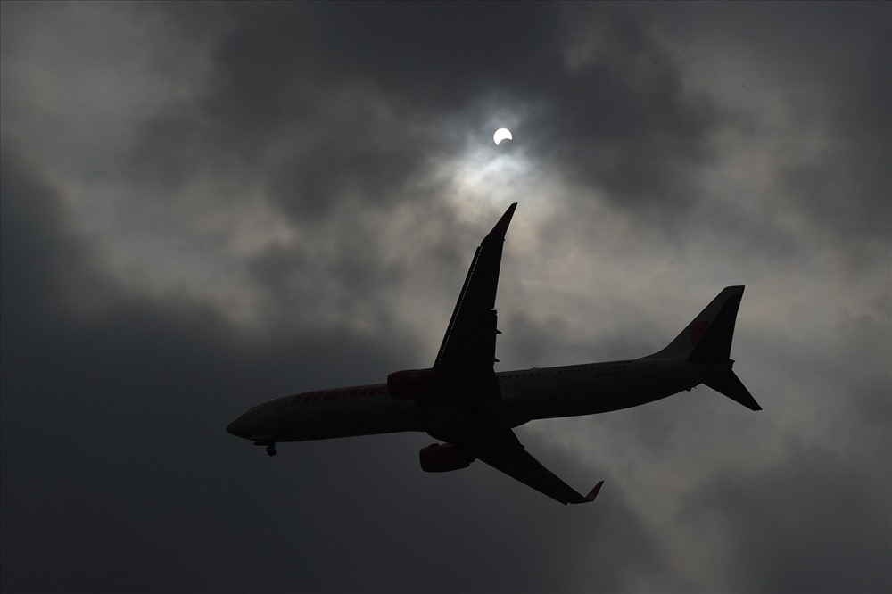 Một chiếc máy bay trên bầu trời khi Mặt trăng di chuyển che khuất Mặt trời được ghi lại ở Hà Nội. Ảnh: AFP.