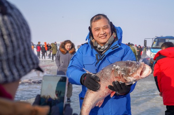 Trong khoảng 4-5 tuần lễ diễn ra lễ hội, du khách được chụp ảnh lưu niệm với những chú cá vừa bị bắt lên dưới hồ nước ngọt nổi tiếng của Trung Quốc. Ảnh TL