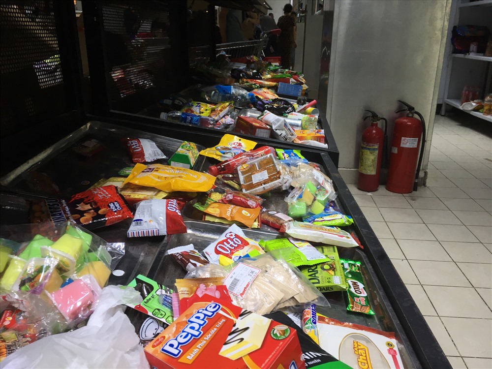 Người tiêu dùng tranh nhau lựa chọn khiến hàng hóa rơi khỏi giá đỡ và nằm vương vãi trên sàn nhà. Nhân viên Auchan phải liên tục xếp lại hàng hóa, nhưng không kịp trước sự “vỡ trận” của người mua hàng.