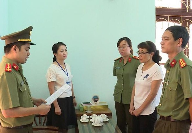 Cảnh sát đọc lệnh khởi tố bị can Nguyễn Thị Hồng Nga (bìa phải).