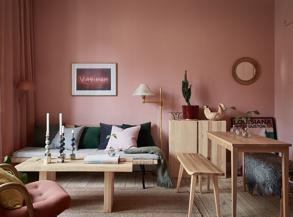 Phòng khách này được phân chia giữa màu hồng phấn và màu gỗ tự nhiên. Gối tựa màu xanh đậm và một vài cây xanh nhỏ trong nhà cũng điểm tô cho căn phòng thêm xinh xắn.