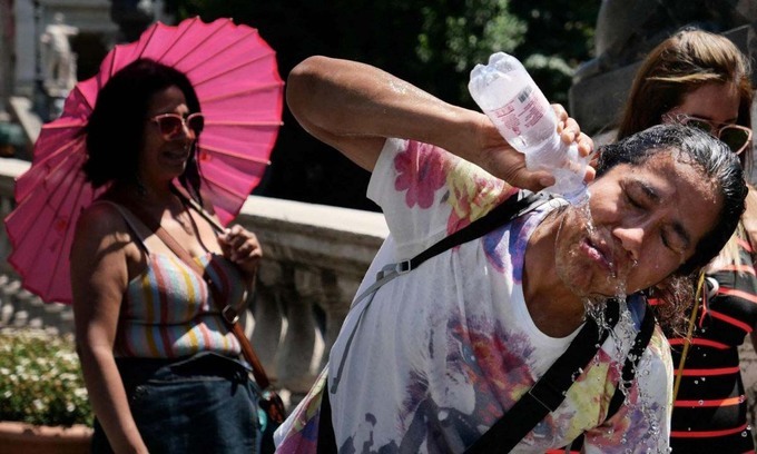 Nữ du khách ở Rome lấy nước dội vào mặt để hạ nhiệt hôm 24.6. Ảnh: AFP.