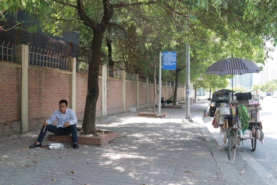 Người bán hàng rong tranh thủ ăn bữa trưa đạm bạc tại vỉa hè phố Nguyễn Chánh (Quận Cầu Giấy).
