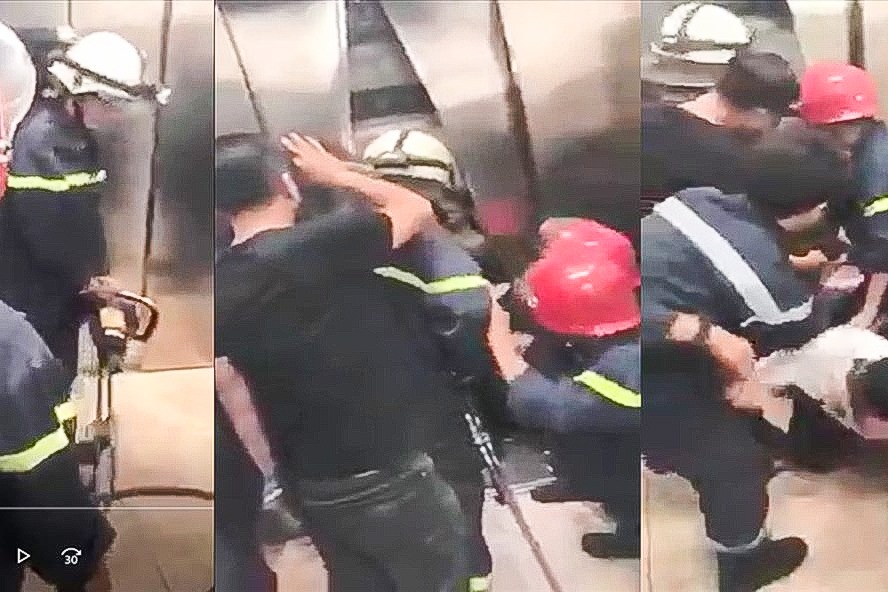 Lực lượng cứu hộ phá cửa thang máy giải cứu nạn nhân. Ảnh cắt từ clip công an cung cấp.