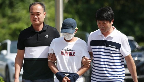 Nghi phạm đánh vợ Việt (giữa) bị cảnh sát Hàn Quốc áp giải hôm 8.7. Ảnh: Yonhap.