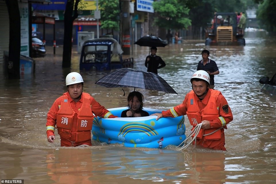 Nhân viên cứu hộ lội qua dòng nước lũ sơ tán một người phụ nữ trên đường phố ở Quảng Tây.