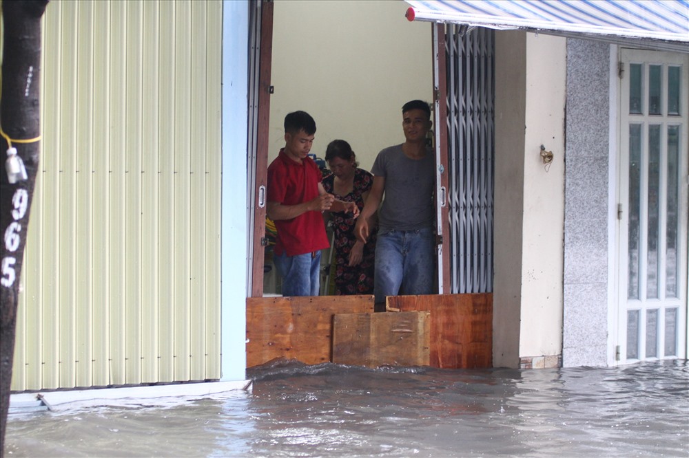 Người dân trên đường Phạm Văn Đồng dùng ván chắn nước khỏi vào nhà.  Ảnh: M.Q